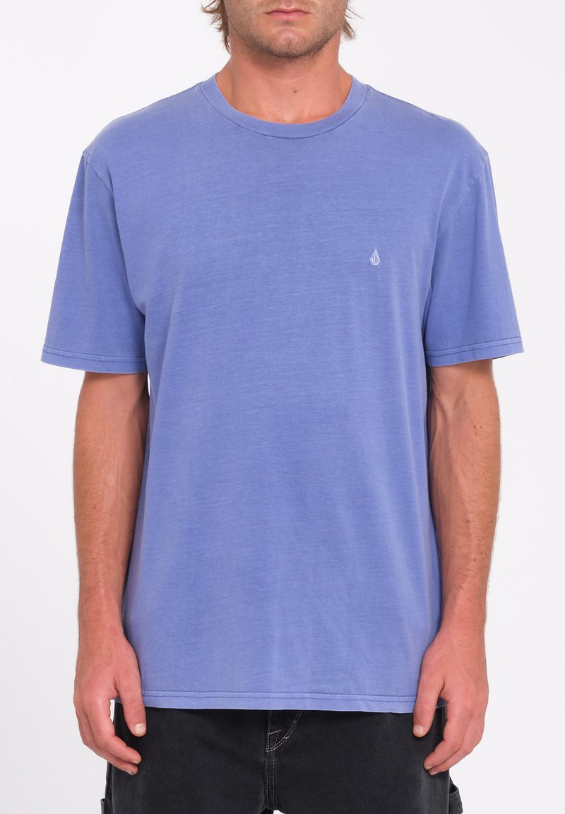 Lyseblå bomulds t-shirt med korte ærmer, rund halsudskæring og en lille logo detalje på venstre bryst. Stoffet har en blød tekstur.
