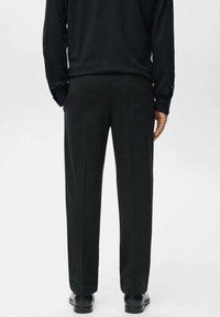 Black trousers with a straight cut. Smooth fabric, no visible patterns. Hem is slightly tapered, paired with black shoes.