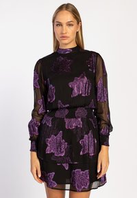 Zwarte jurk met doorzichtige mouwen en een geraffineerde taille, met een paarse bloemenprint. Soepele textuur met een hoge halslijn en gelaagd ontwerp.