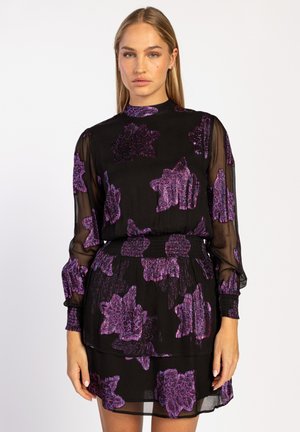 Zwarte jurk met doorzichtige mouwen en een geraffineerde taille, met een paarse bloemenprint. Soepele textuur met een hoge halslijn en gelaagd ontwerp.