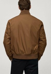 Veste bomber marron à texture lisse, col et poignets côtelés, taille élastique, coupe décontractée. Pas de quincaillerie visible ni de motifs.