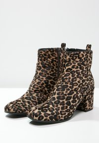 Bottes à cheville en imprimé léopard faites d'un tissu texturé, avec un bout arrondi, un talon carré et une fermeture éclair sur le côté.