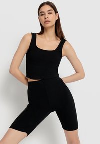 Schwarzes geripptes Crop Top und passende hochgeschnittene Shorts. Der Stoff hat eine weiche Textur, mit einem quadratischen Ausschnitt und figurnaher Passform.