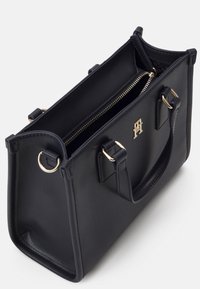 Svart lærveske med gullhardware, to håndtak og en glidelåsinnvendig lomme. Teksturert overflate med strukturert form.