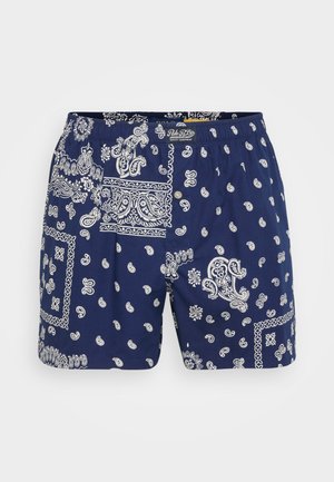 Shorts de bain bleu marine avec un motif paisley blanc, taille élastique, fermeture à bouton et tissu léger à la texture lisse.