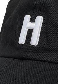 Zwarte pet van textiel met een grote, geborduurde witte letter "H" op de voorkant, met strakke lijnen en een eenvoudig ontwerp.