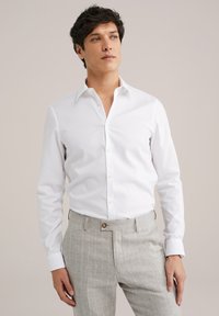 Witte overhemdd met een verspreide kraag en knoopsluiting, gecombineerd met lichtgrijze gestreepte broek, met een soepele stoftextuur.
