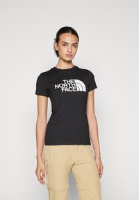 Černé bavlněné tričko s výrazným bílým logem The North Face. Úzký střih s krátkými rukávy a kulatým výstřihem.