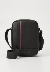 Borsa a tracolla nera con trama, tracolla regolabile, dettaglio a striscia verticale rossa e bianca e logo "Tommy Hilfiger" sulla parte anteriore.