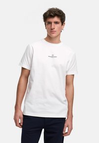 Hvit bomulls T-skjorte med rund hals, med en svart logo trykk på brystet. Enkel, kort erm, og klassisk passform.