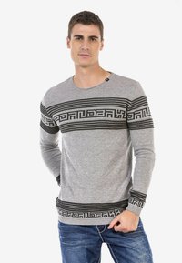 Grauer langärmeliger Pullover mit schwarzen gemusterten Streifen über der Brust und an den Ärmeln. Hergestellt aus weichem Stoff, mit einem Rundhalsausschnitt.