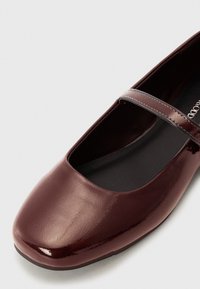 Glossy burgundy ballet flat with a square toe and a thin strap across the instep; smooth texture and minimalistic design.