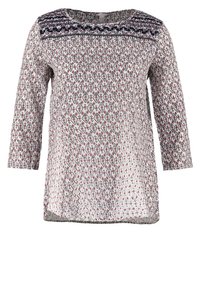 Blouse à manches longues avec un motif géométrique en losanges bleu marine, rouge et blanc. Encolure ronde avec des coutures décoratives aux épaules.