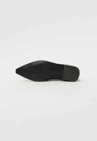 Zapato de tacón alto negro con punta afilada y parte superior de cuero suave. La suela de goma texturizada presenta un patrón sutil para ofrecer agarre.