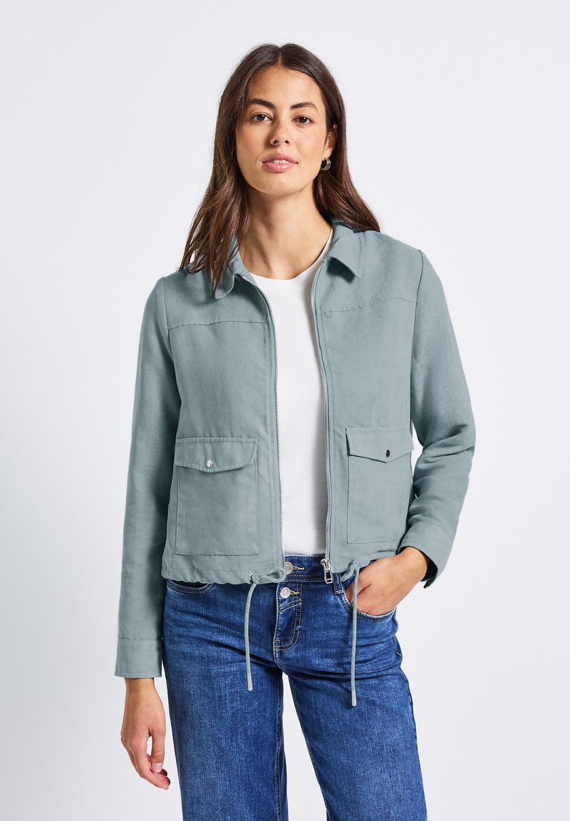 Ljus teal-färgad zip-up jacka i mjukt tyg, med krage, två framfickor och justerbar dragsko i nederkant för en skräddarsydd passform.