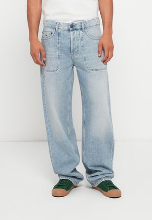 Lyseblå vide jeans laget av denim, med frontlommer og en falmet tekstur. Kombinert med grønne snørestøvler.