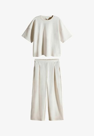 To-delt outfit i let beige, bestående af en kortærmet top og brede bukser. Stoffet ser blødt ud, med en glat tekstur og plisserede detaljer.