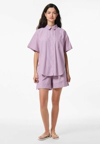 Camicia a maniche corte con colletto e pantaloni corti abbinati in viola chiaro con strisce bianche. Chiusura con bottoni e dettaglio della tasca sulla camicia.