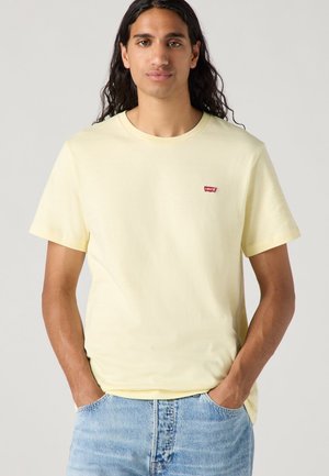 Helles gelbes Baumwoll-T-Shirt mit rundem Halsausschnitt und kurzen Ärmeln; verfügt über ein kleines rotes Levi’s-Logo auf der linken Brust.