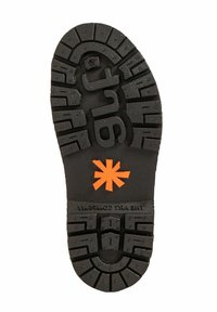 Suela de zapato de goma negra con surcos profundos. Presenta un logo de asterisco naranja y letras en relieve, proporcionando agarre y durabilidad.