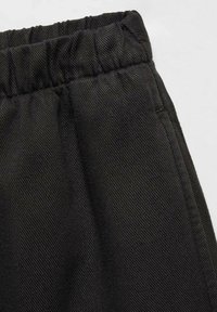 Pantaloni negri țesuti, cu talie elastică, având o suprafață texturată și buzunare laterale. Materialul prezintă un model diagonal subtil.
