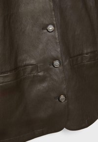 Giacca di pelle marrone scuro con una superficie liscia, due tasche frontali e bottoni metallici con un design circolare.