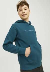Sudadera con capucha en color azul verdoso, con un bolsillo frontal y puños acanalados, presenta el texto blanco "JACK & JONES" en el pecho. Textura de tela suave.
