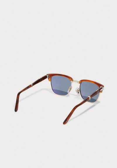 Ochelari de soare cu rame pătrate, din material tortoise-shell, lentile în nuanțe de albastru, detalii din metal și brațe elegante de culoare maro. Au pernuțe pentru nas pentru un confort sporit.