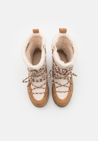 Brune vinterstøvler med en plys kremfarget shearling-overdel, mønstrede snører, gullfargede detaljer og en teksturert gummisåle.