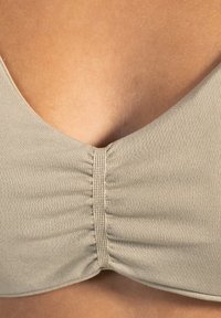 Haut de bikini beige avec un décolleté en V profond. Comprend un tissu froncé au centre et un matériau lisse et extensible.