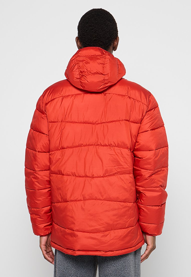 Chaqueta de plumas roja con capucha, que presenta un diseño acolchado y una textura suave. Puños elásticos y una silueta ligeramente recortada.