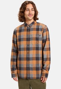 Heren flanellen overhemd met een oranje, grijs en zwart geruit patroon, button-down kraag, borstzak en lange mouwen van een zachte stof.