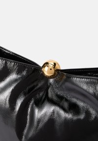 Schwarze Lackleder-Clutch mit einem gerafften Design und einem goldenen, runden Verschluss, der mit "Furla" gekennzeichnet ist. Glatte Textur mit glänzender Oberfläche.