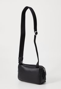 Černá crossbody taška vyrobená z hladké umělé kůže, obdélníkový tvar, nastavitelný černý popruh, stříbrný zip s táhlem, minimalistický design.