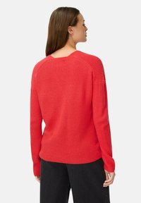 Roter gestrickter Pullover mit langen Ärmeln, ausgestattet mit einem Rundhalsausschnitt und geripptem Muster; mittellang mit lockerer Passform und versetzten Schulternähten.