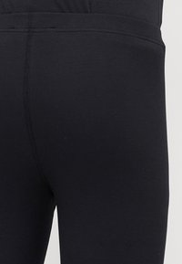 Μαύρο ριμπ κολάν με λεία υφή, ελαστική μέση και εφαρμοστή γραμμή, χωρίς ορατά σχέδια ή λεπτομέρειες υλικού.