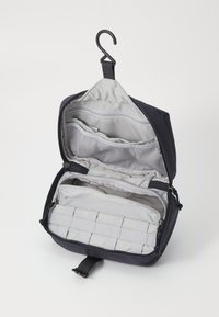 Black travel bag with a hook for hanging, featuring multiple compartments and mesh pockets, grey interior fabric with a textured panel.