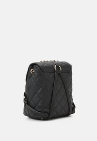 Mochila negra acolchada hecha de material sintético texturizado, con herrajes en tono dorado, una correa de cadena y un cierre de cordón.