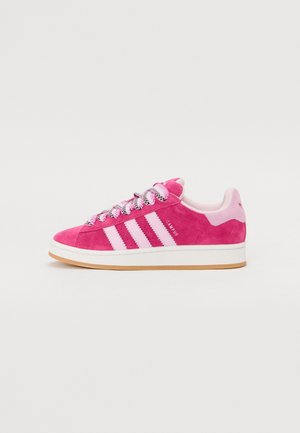 Roze suède Adidas Campus sneaker met witte strepen, patroonveters en een gum rubberen zool op een witte achtergrond.