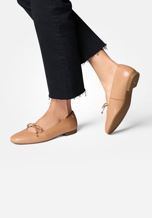 Ballerines en cuir beige clair avec un bout rond, accent noué sur le devant et un petit talon plat. Associées à un pantalon noir 7/8.