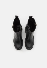 Bottes de cheville en cuir noir avec un bout arrondi, une fermeture éclair sur le côté et une semelle en caoutchouc texturé. Fini lisse et design minimaliste.