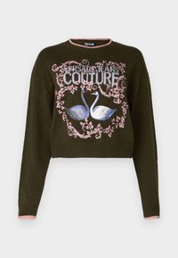 Maglione accorciato in maglia verde scuro. Presenta una grafica di due cigni circondati da motivi floreali, con colletto e orli delle maniche in rosa chiaro.