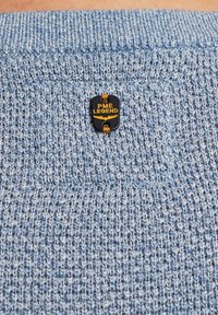 Hellblauer Strickpullover mit strukturiertem Muster, versehen mit einem schwarzen PME Legend Etikett. Der Kragen ist gerippt und ausgeprägt.