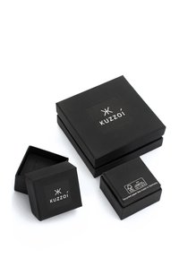Schwarze Verpackungsboxen in verschiedenen Größen mit glatter, matter Textur, auf einer Box befindet sich das weiße "KUZZOI"-Logo sowie Informationen zur Wiederverwertung.