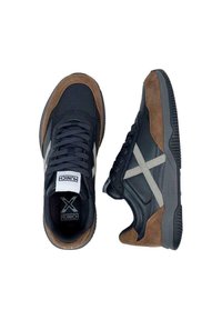 Sneaker neri e marroni con tomaia in pelle e suede, logo 'X' grigio sui lati e suola in gomma texturizzata.