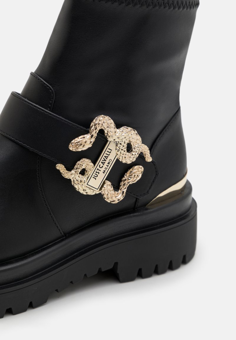 Czarne skórzane botki za kostkę z grubą podeszwą i złotym zapięciem w kształcie węża z wytłoczonym logo. Teksturowana cholewka z akcentem w postaci paska.
