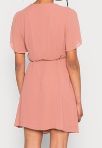 Krótka sukienka w odcieniu różu z lekkiego szyfonu, z krótkimi rękawami, talią podkreśloną paskiem oraz rozkloszowanym dołem o miękkiej fakturze.