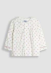 Camicia bianca a maniche lunghe con piccoli motivi floreali rosa, colletto scallop e bottoni sul davanti; presenta accenti rosa sulle maniche.