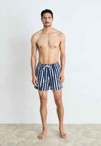 Marineblaue und weiß gestreifte Badeshorts mit einem elastischen Bund und verstellbarem Kordelzug, aus leichtem, atmungsaktivem Material.