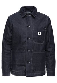 Tmavě modrá džínová bunda s knoflíkovým zapínáním vpředu, límcem s výrazným hrotem, náprsní kapsou s logovou nášivkou a dvěma předními kapsami. Celek zdobený kontrastním šitím.